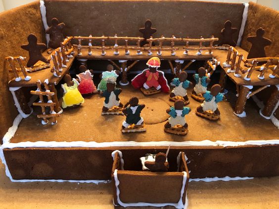 Gingerbread house decorated as stage with people from Hamilton the musical. 